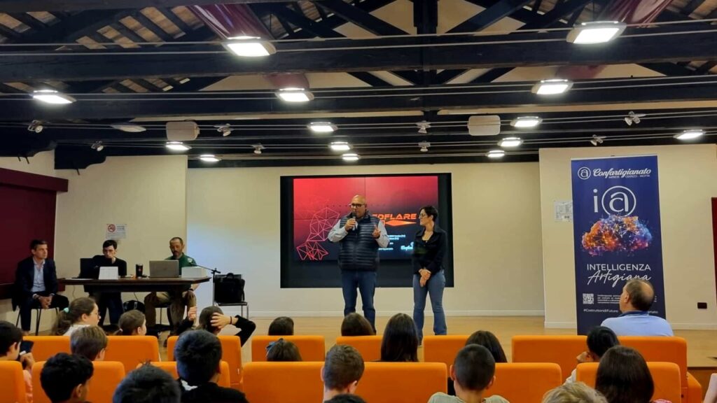 Foto del dirigente scolastico e degli esperti di cybersecurity sul palco durante l'evento di hacking e sensibilizzazione alla sicurezza informatica nelle scuole medie.